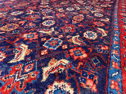 Carpet detail: dark blue with red-orange ornaments and white accents, woven texture