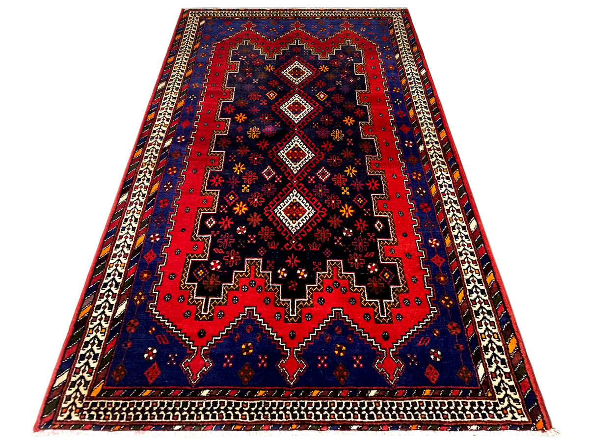 Runner rug in angled view: dark blue, red pattern, beige frame and borders