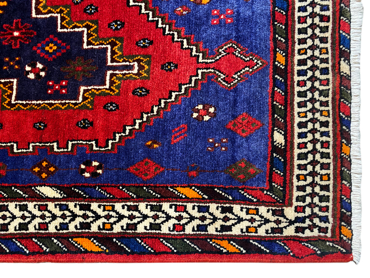 Sirjan runner rug corner with a red background, blue pattern, and beige border