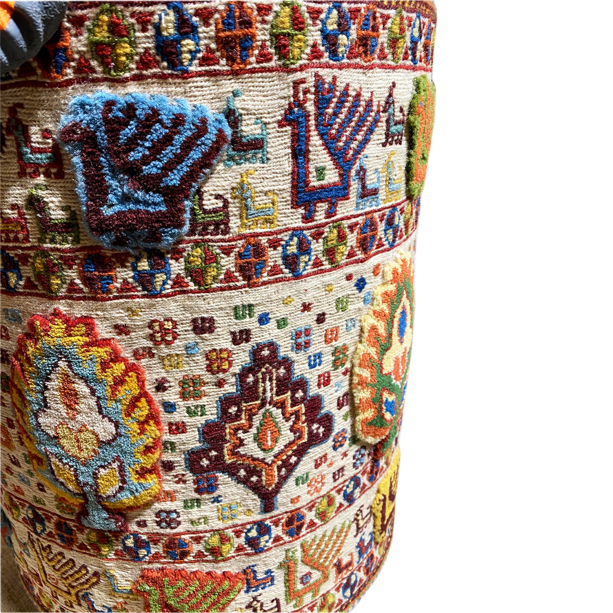 Close-up: wool stool cover with a blue motif and colorful carpet pattern