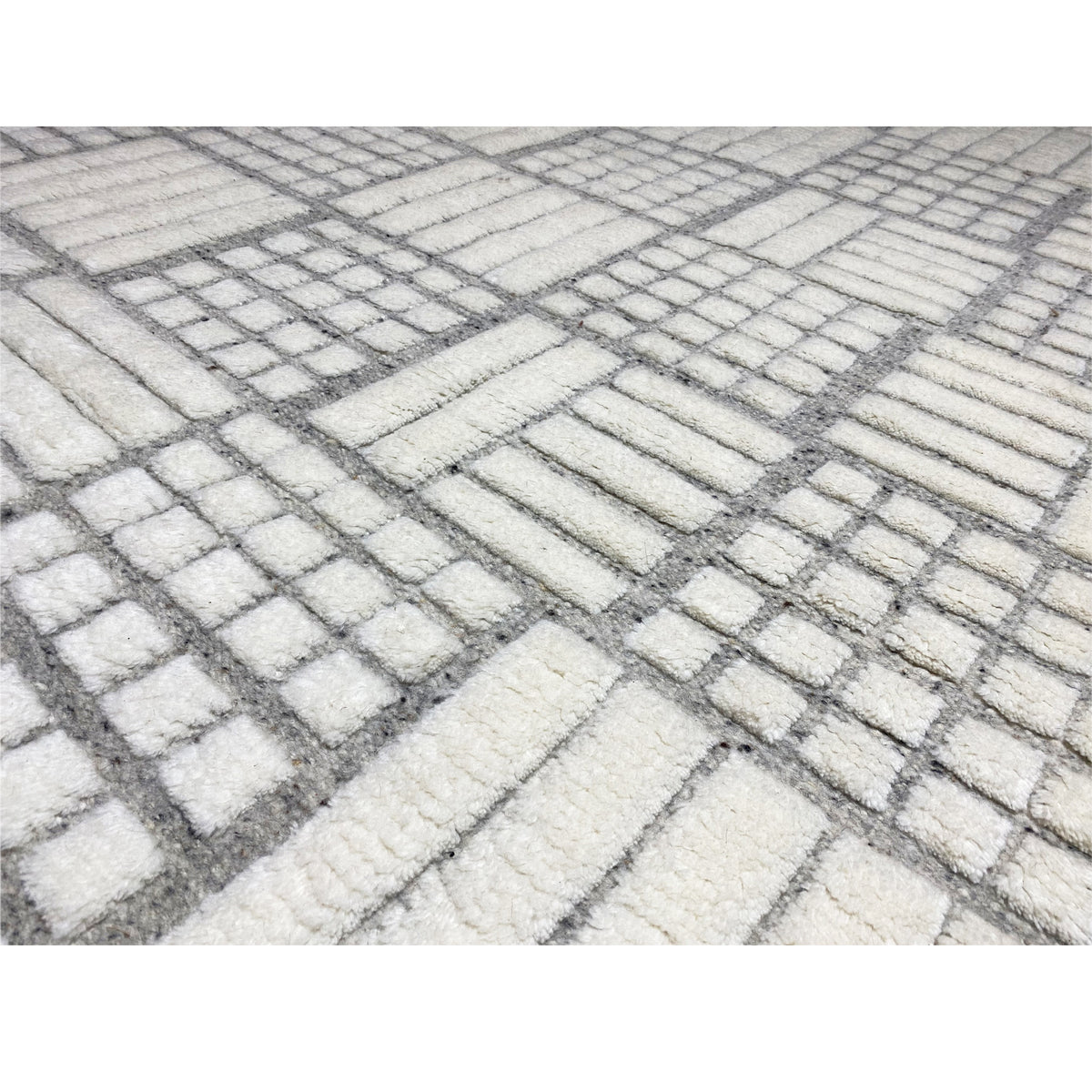 Close-up: Berber rug with a woven white and gray grid, fringes