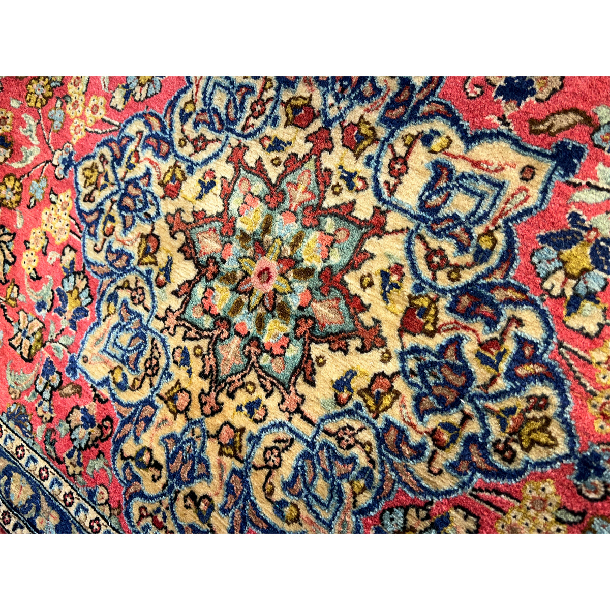 Close-up of a carpet surface with a red background, blue vine ornament, and colorful details