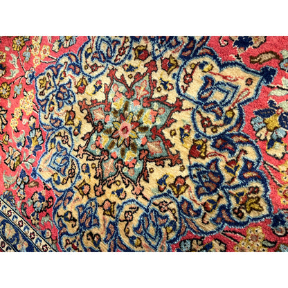 Close-up of a carpet surface with a red background, blue vine ornament, and colorful details