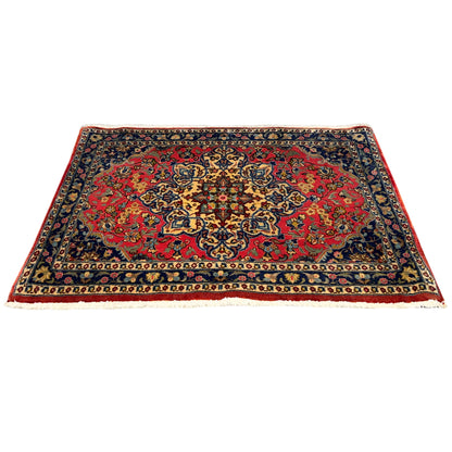 Rug front view: red ornamental pattern, dark blue border, clean bound edges