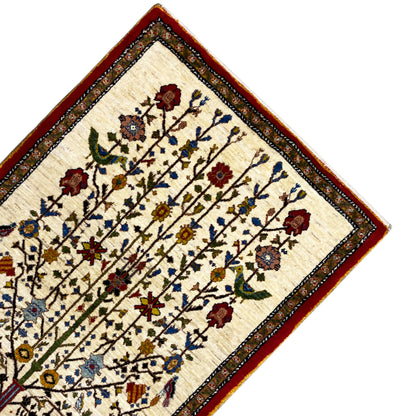 Gabbeh rug corner with a beige background, red decorative band, and small floral motifs