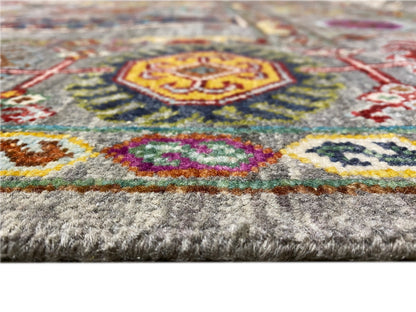 Detail: grauer Flor mit buntem Motiv und farbiger Bordürenkante, mit Fransen am Rand.