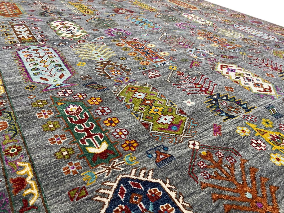 Nahaufnahme: grauer Teppich mit bunten Kreuz- und Rautenmustern im Feld.
