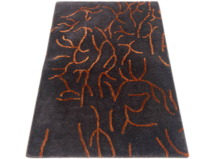 Rectangular designer rug, dark gray with an orange abstract pattern, angled