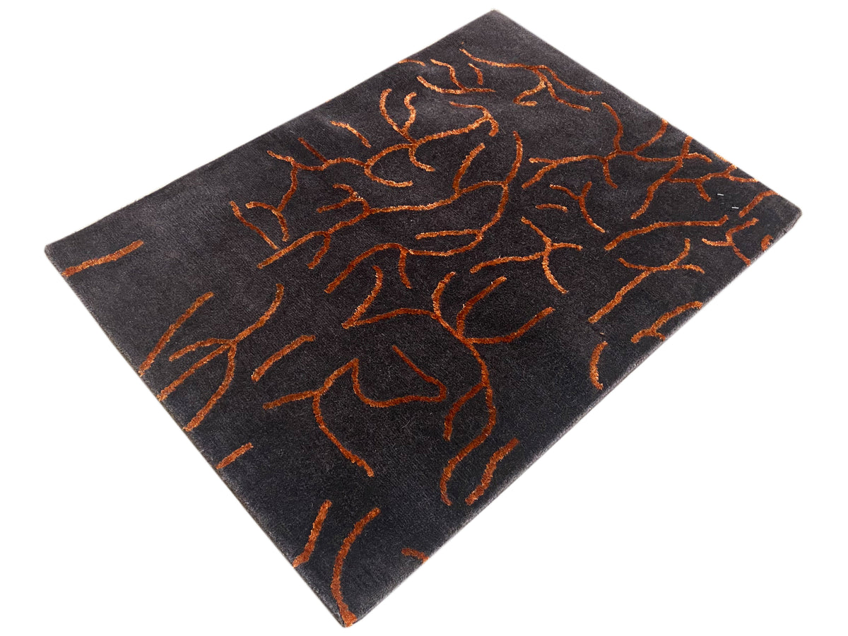 Designer rug, dark gray with an orange abstract pattern, square, viewed at an angle