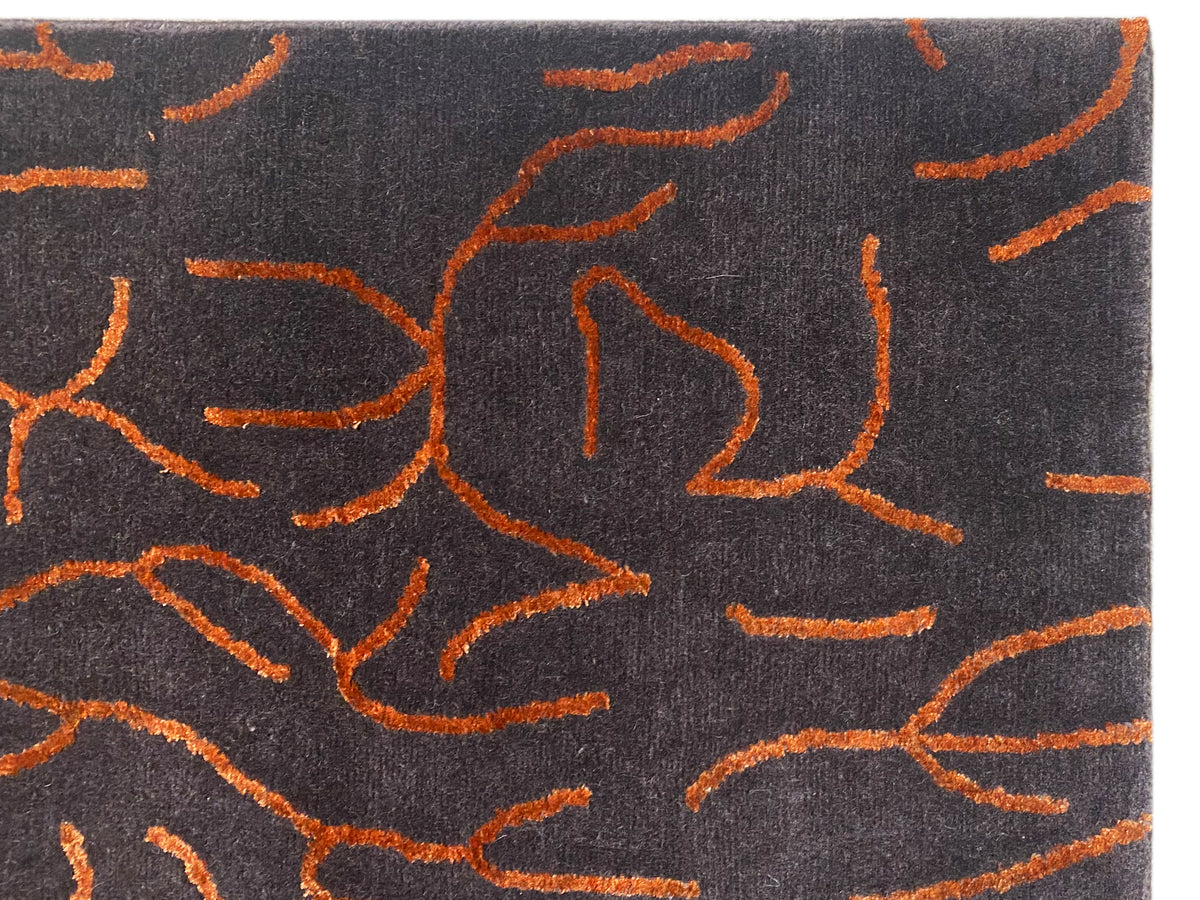 Close-up of the designer rug: dark gray pile with orange abstract lines