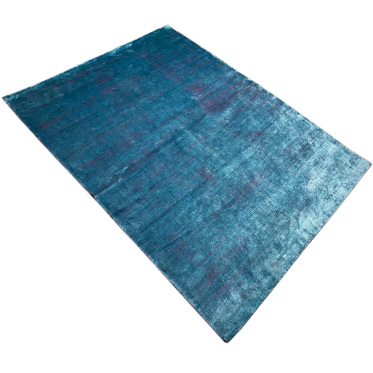 Designer rug in blue with a mottled surface and an even pattern, laid diagonally