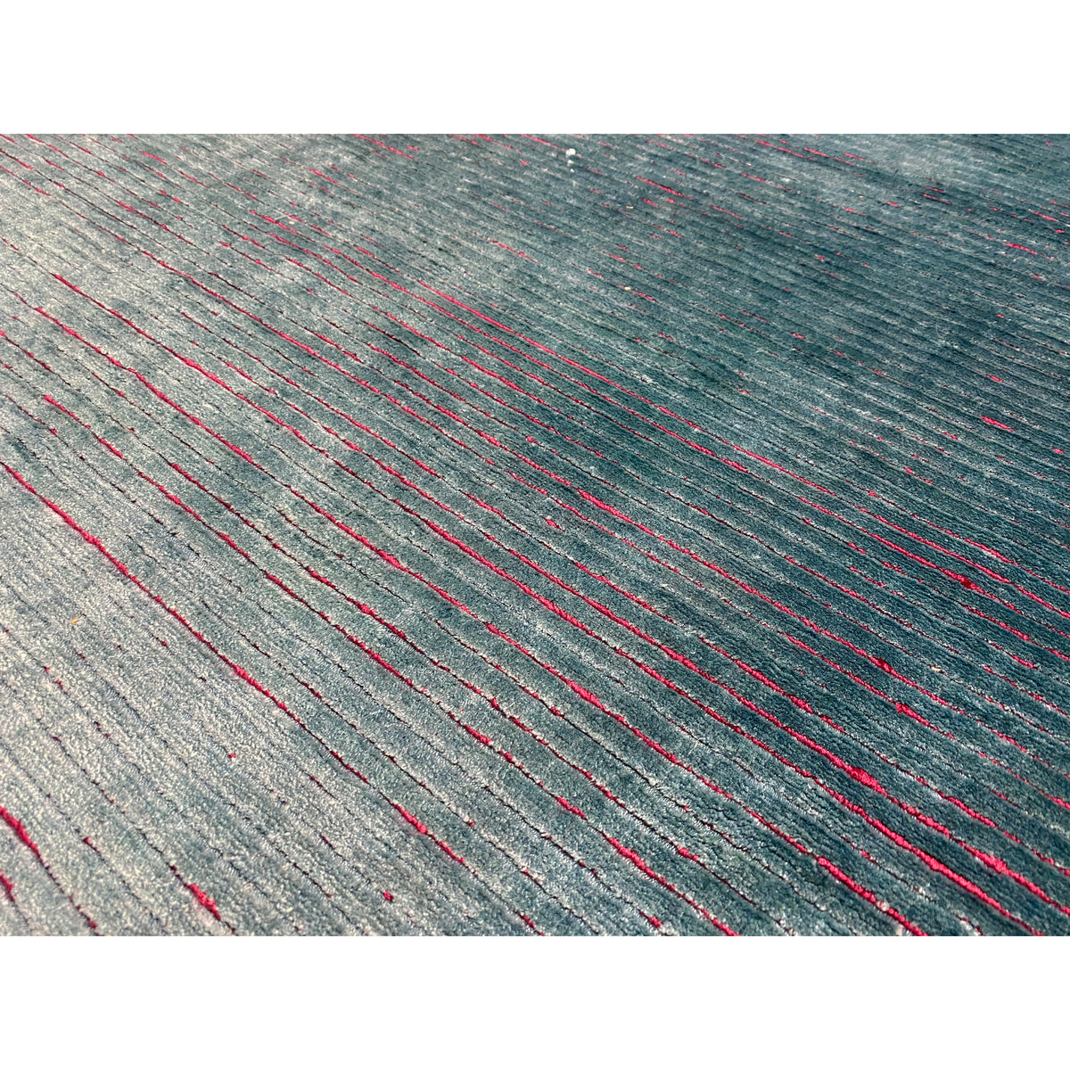 Close-up of a designer rug: gray-blue weave with red and blue thread accents