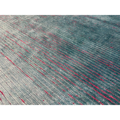 Close-up of a designer rug: gray-blue weave with red and blue thread accents