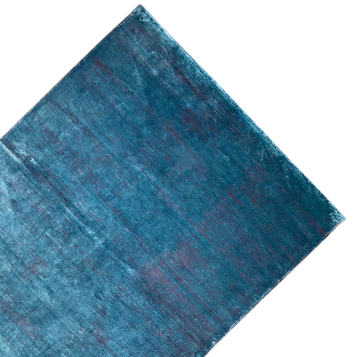 Designer rug in blue with a visible woven texture, photographed diagonally