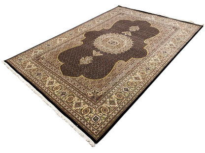 Teppich von oben: dunkelbraunes Medaillon mit beigen Ornamenten, Bordürendetails, Fransen