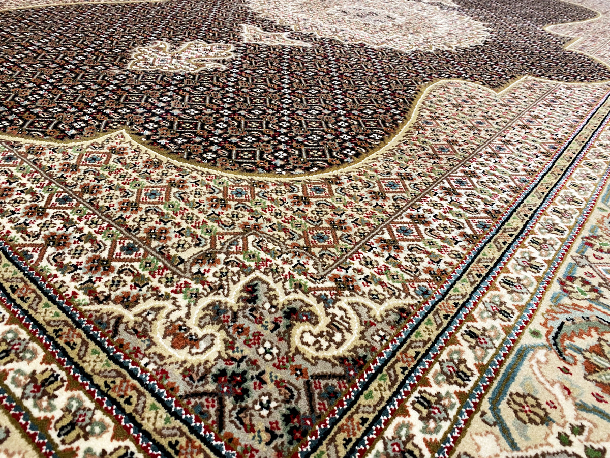 Teppichdetail mit braunem Ornamentfeld, beigem Rahmen, mehrfarbigen Blüten und Bordüre