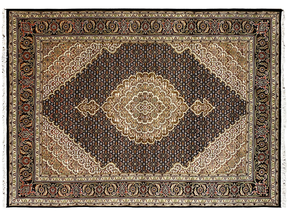Rechteckiger Indo-Tabriz Teppich mit dunklem Ornamentfeld, beigem Medaillon und Zierbordüre.