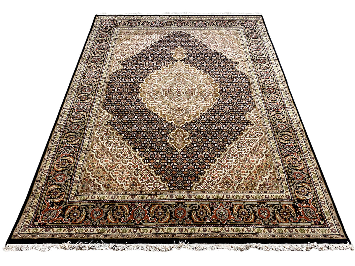 Rechteckiger Teppich mit beigem Mittelmedaillon, dunklem Musterteppich und Zierbordüre, Fransen.