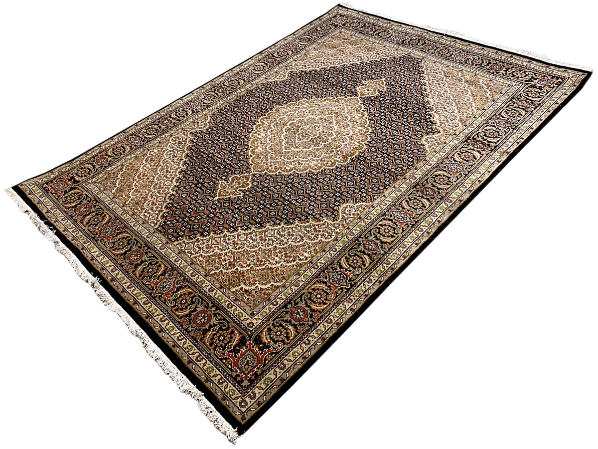 Rechteckiger Teppich mit zentralem Medaillon, dunklem Ornamentmuster, Zierbordüre und Fransen.