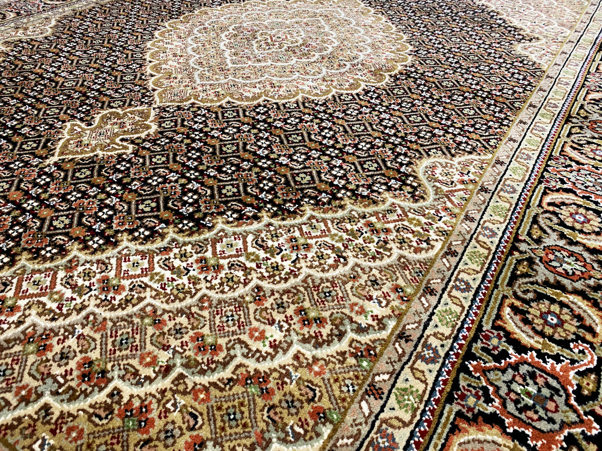 Teppich-Detail: zentrales beiges Medaillon auf dunklem Ornamentgrund, mehrfarbige Muster.