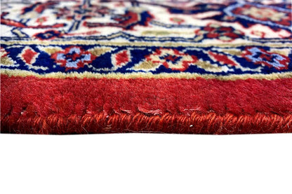 Close-up of a Bidjar carpet: red pile with a colorful striped pattern along the edge