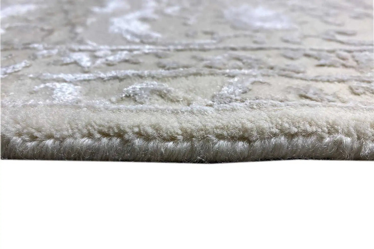 Close-up of a carpet edge with dense, short pile and a light beige relief pattern.