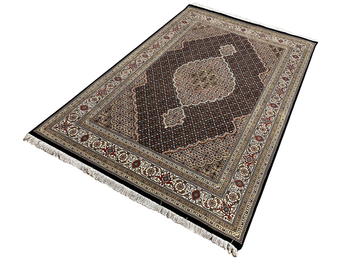Tabriz-style rug at an angle with a medallion and fringes at one corner