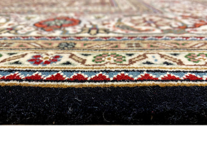 Side view of a Tabriz-style rug: border pattern at the top, dark pile and edge binding