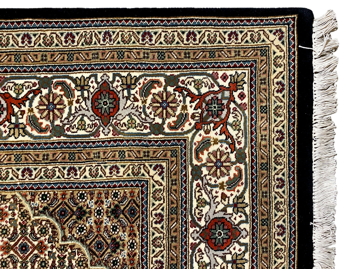 Tabriz-style rug with a detailed border around the edge and white fringe at the corner