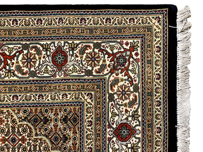 Tabriz-style rug with a detailed border around the edge and white fringe at the corner