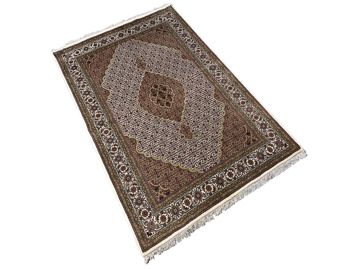Indo Tabriz rug: angled view of the patterned area with a central flower and fringes