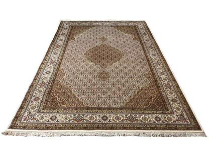 Rug: Corner view in beige/brown with an ornamental border and tassel fringe along the edge.