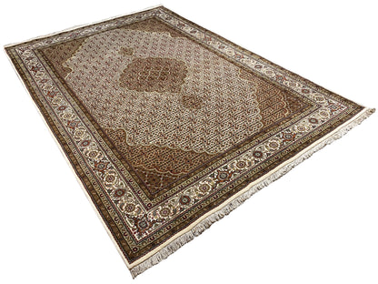 Beige and brown rug spread out, photographed diagonally, with a decorative border and fringes.