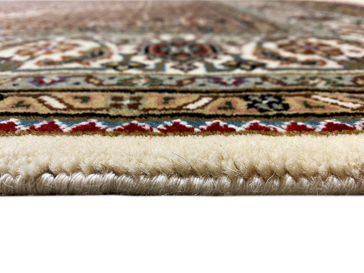 Indo Tabriz carpet detail: pile and border pattern with fringes, cream-colored background