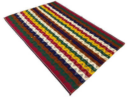 Jajim rug at an angle with multicolored zigzag stripes and fringes