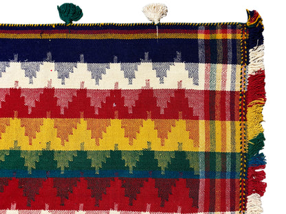 Close-up of a jajim rug: striped pattern with tassels in blue, green, red, and yellow