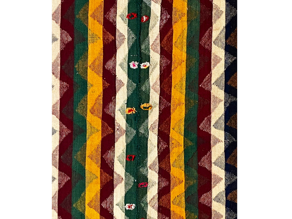Close-up of a Jajim rug with striped colors and embroidered floral motifs