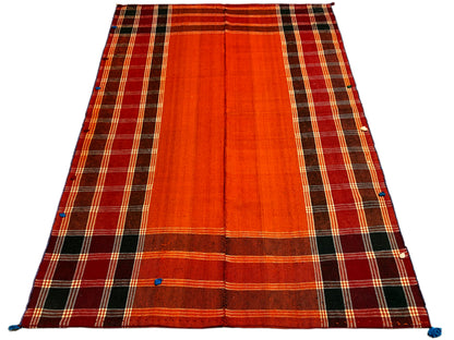 Jajim rug, lying at an angle: red-orange surface with a dark checkered border and blue fasteners
