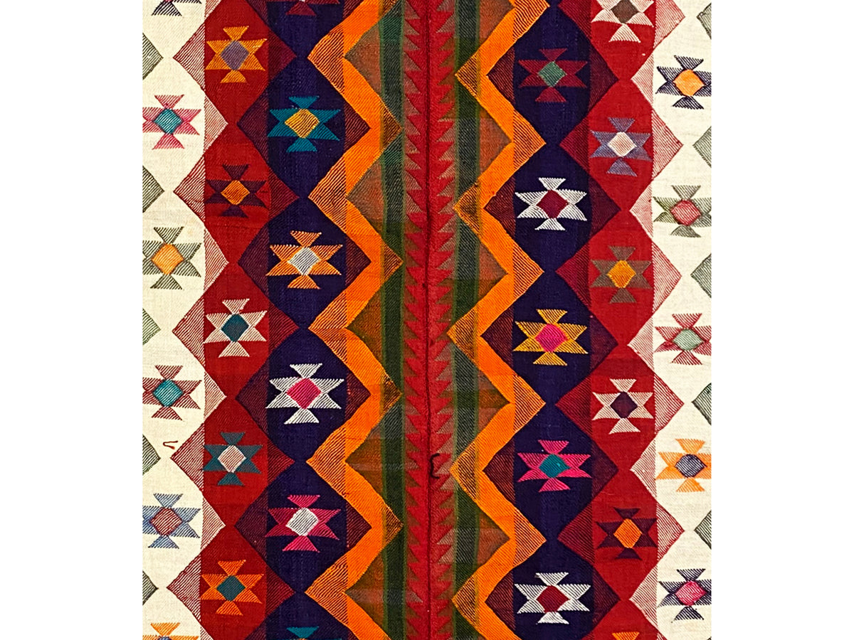 Jajim rug detail: red, blue, and orange geometric shapes on a light background