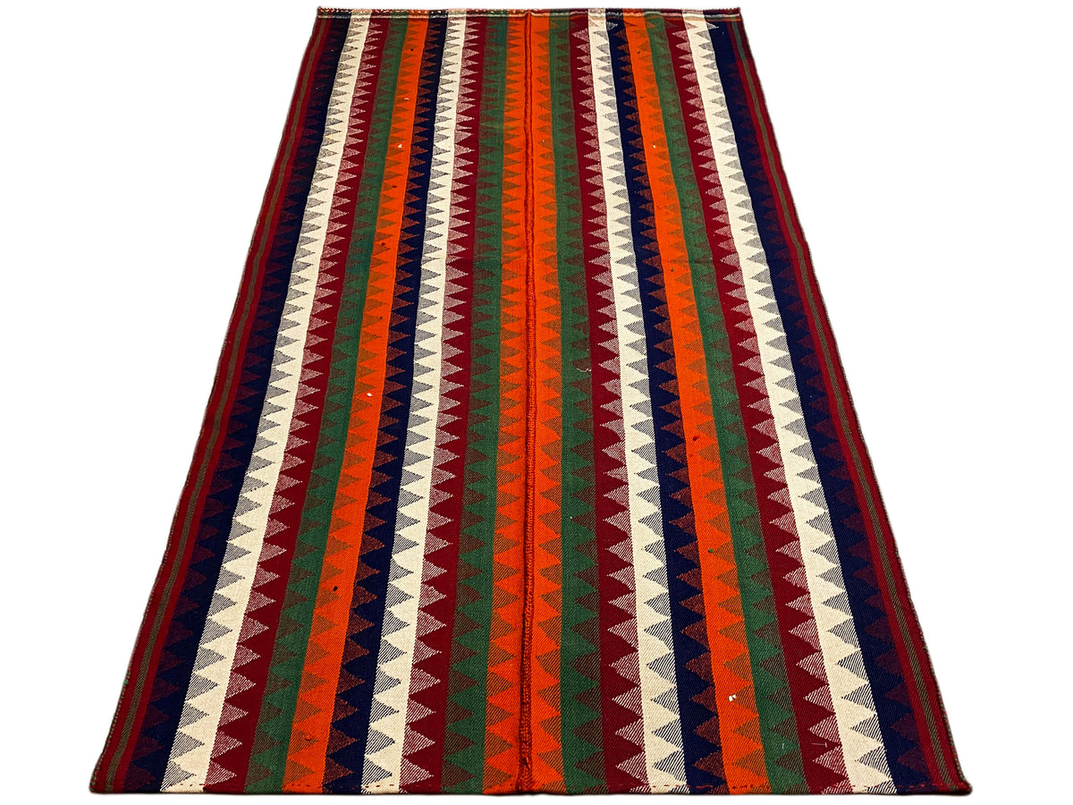 Jajim rug in an angled view: multicolored zigzag stripes with a dark border