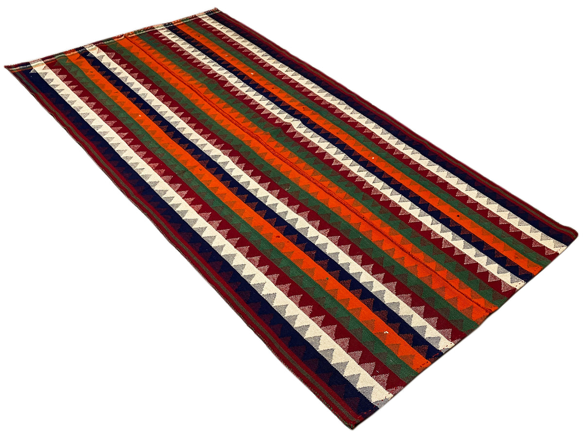 Jajim rug folded at an angle: wide zigzag and striped bands, multicolored