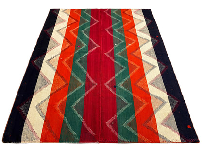 Rug with a geometric zigzag and stripe pattern in red, green, orange, and dark blue