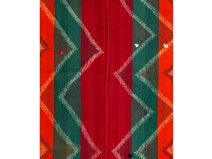 Carpet detail with a woven central band in red, flanked by green and orange zigzags