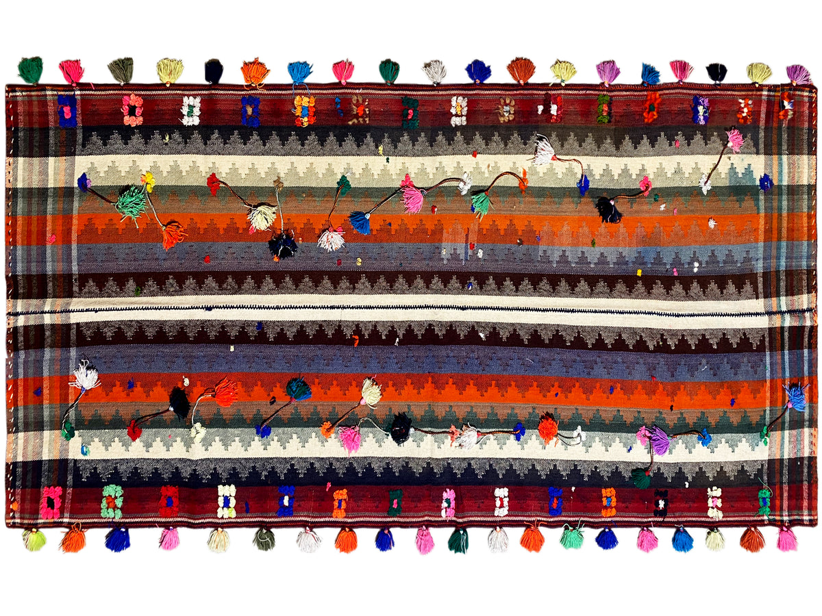 Multicolored striped rug with floral motifs, decorative border, and tassels