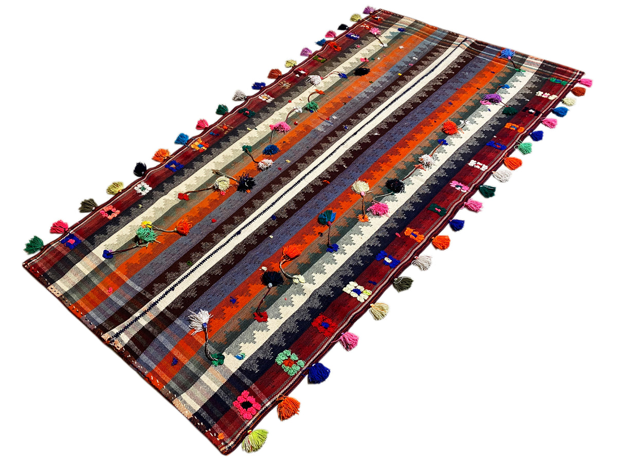 Angled Jajim rug with a striped pattern and multicolored tassels