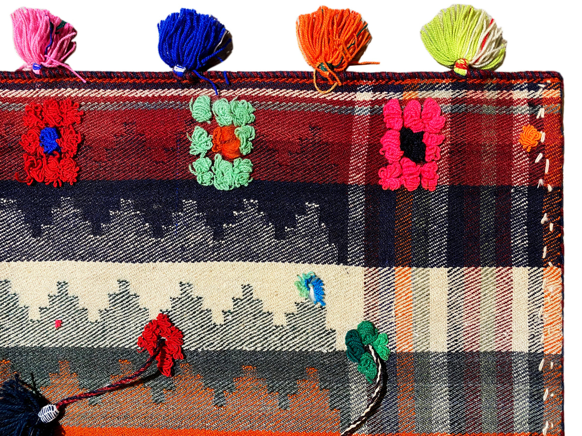 Close-up: Jajim rug with a checkered pattern, floral motifs, and multicolored tassels