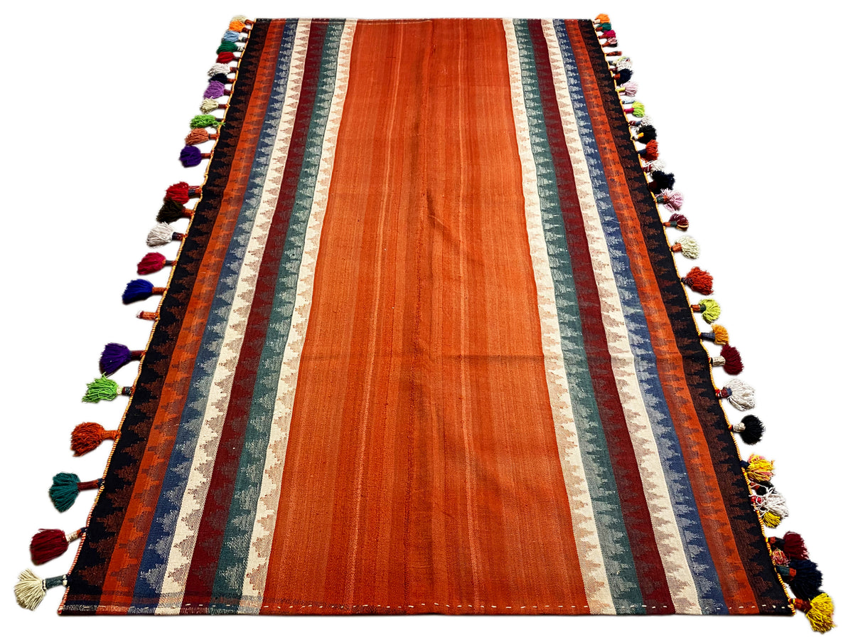 Jajim rug in terracotta with striped borders and colorful tassels along the edges