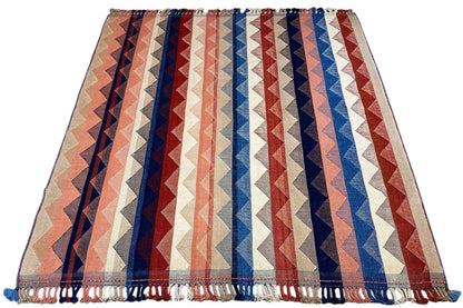 Rectangular rug with a zigzag pattern in beige, blue, red, and white stripes, fringes