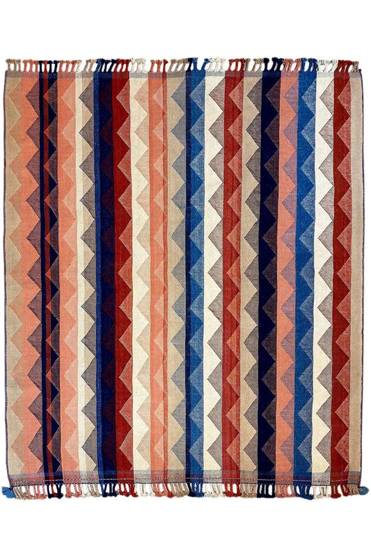 Rectangular rug with zigzag stripes in blue, red and beige, with a fringed edge