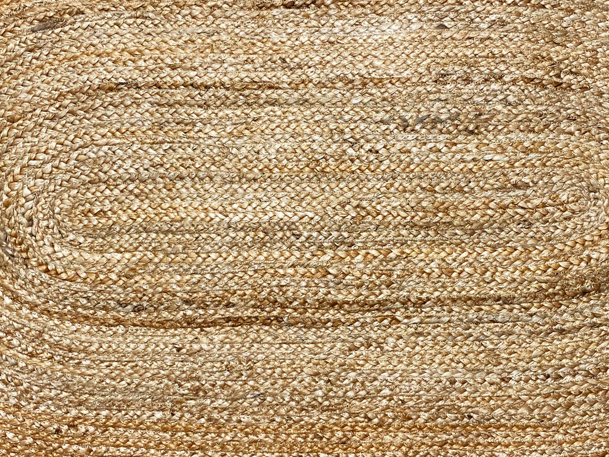 Close-up of a jute rug: beige woven pattern with fine, parallel lines and a spiral zone.